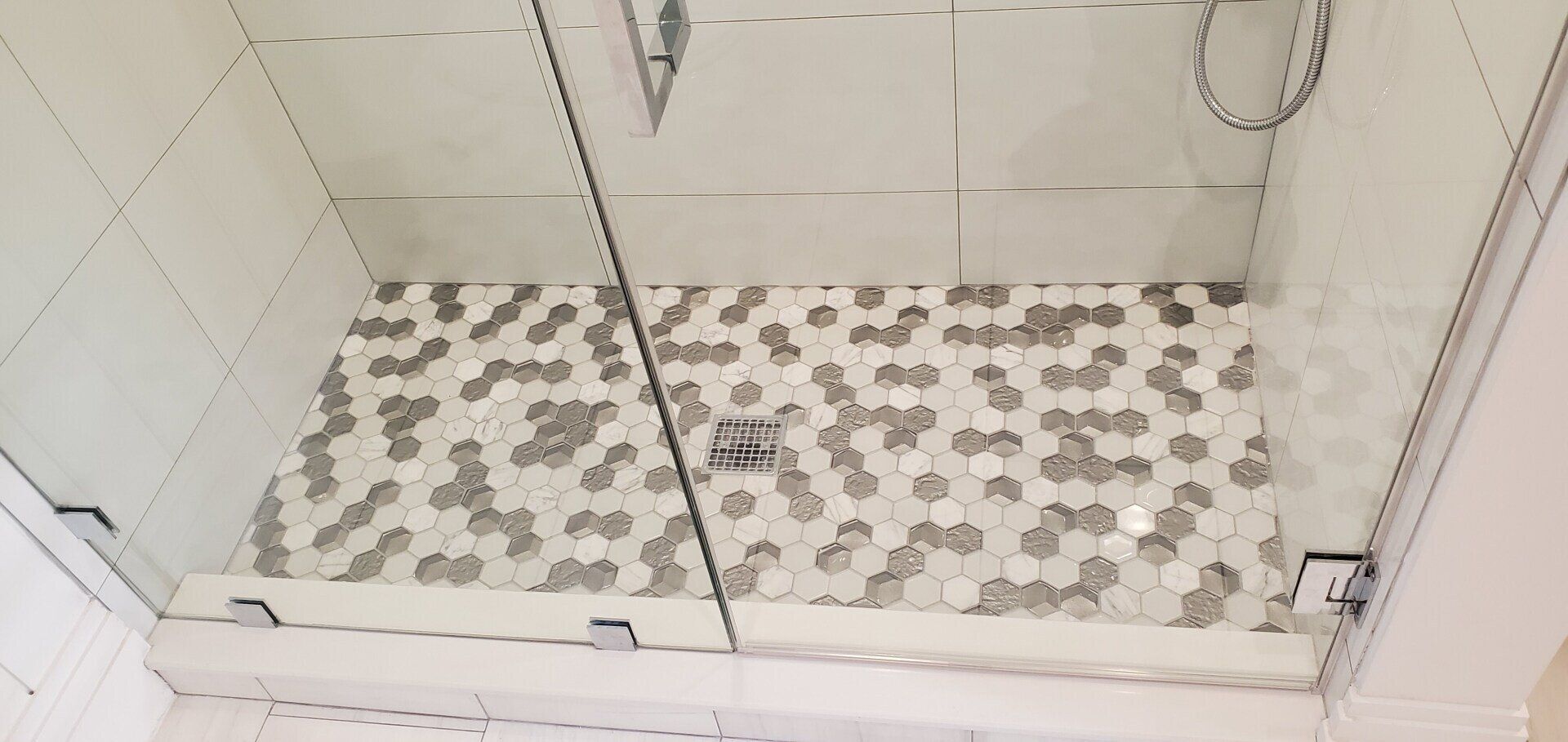 a shower stall with a tiled floor and a glass door .