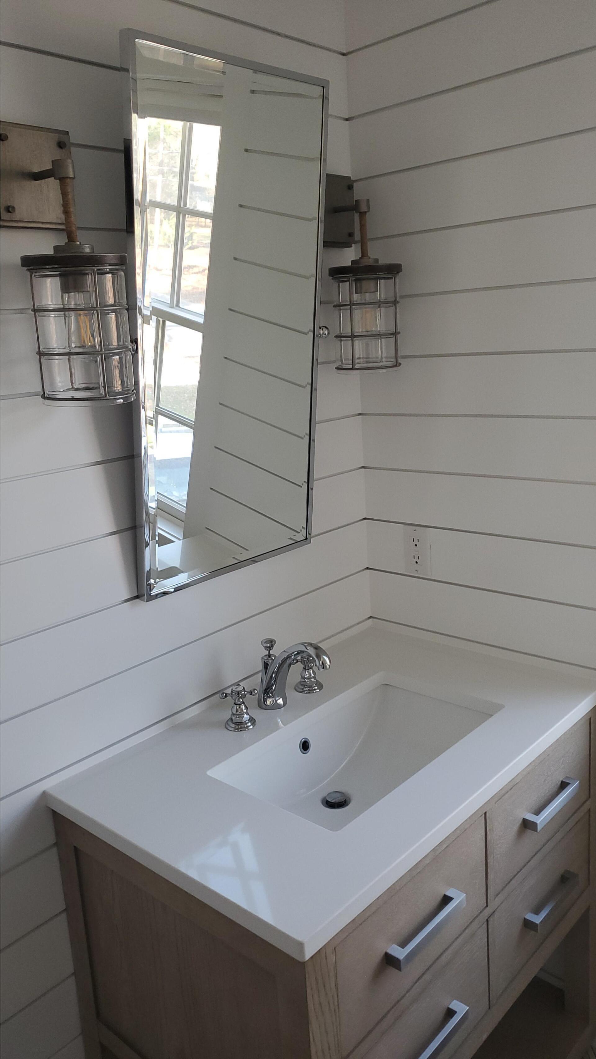 a bathroom with a sink , mirror and drawers .
