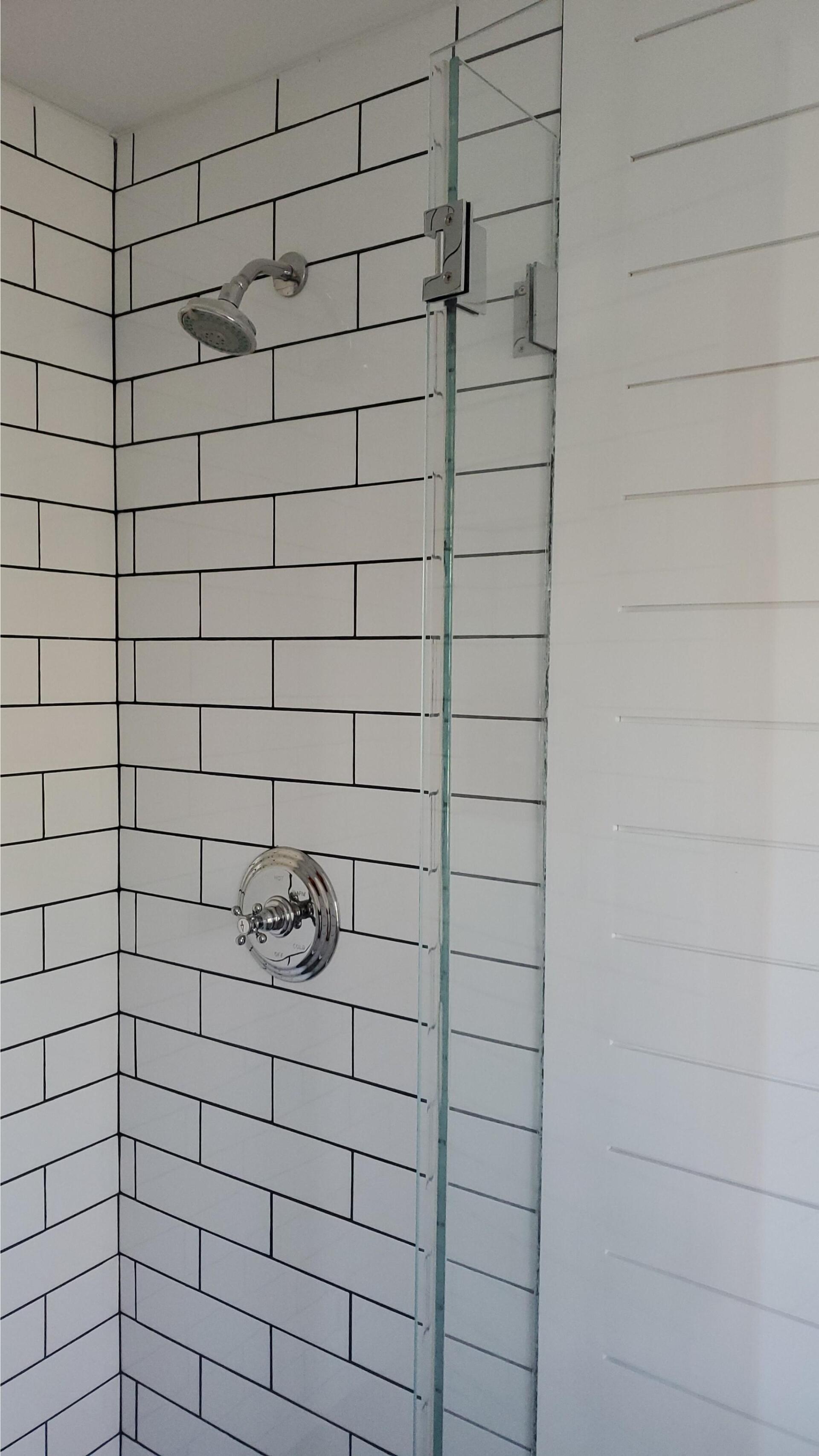 a shower with white tiles and a glass door