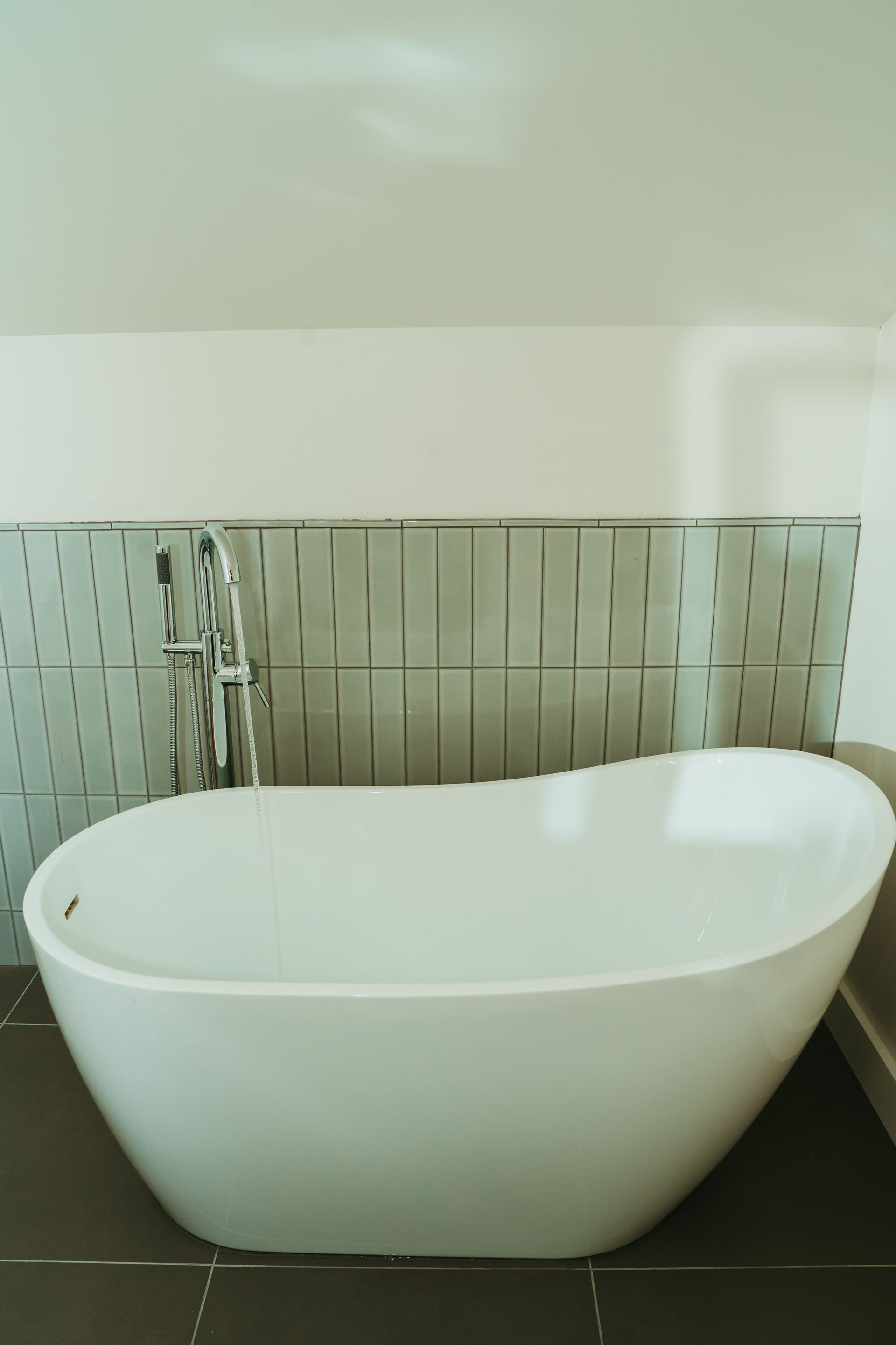 A white bathtub is sitting on a tiled floor in a bathroom.