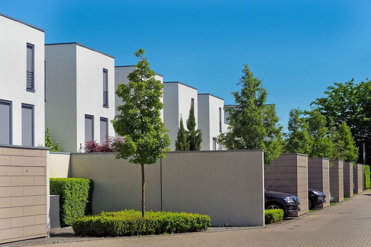 A row of white rental and leased houses with cars parked in front of them.