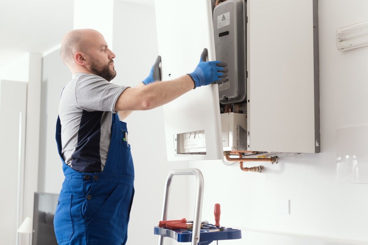 A man is working on a boiler in a kitchen.