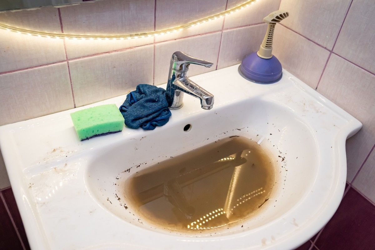A bathroom sink with brown water coming out of it.