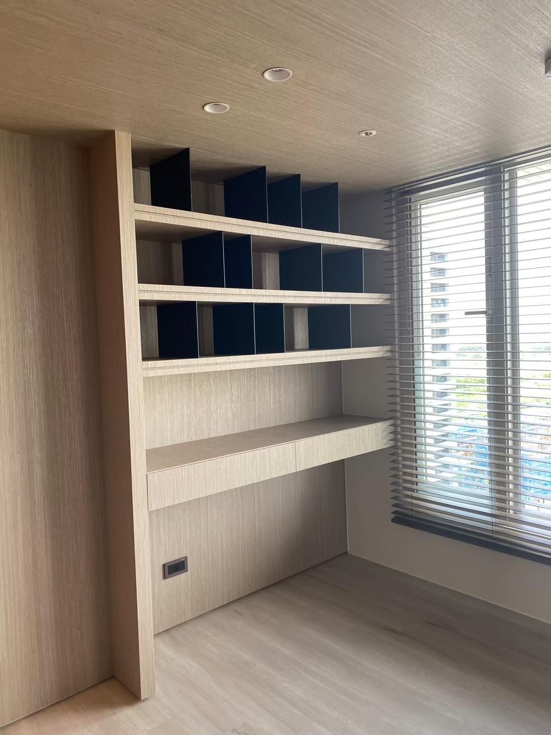 A room with shelves and a window with blinds.
