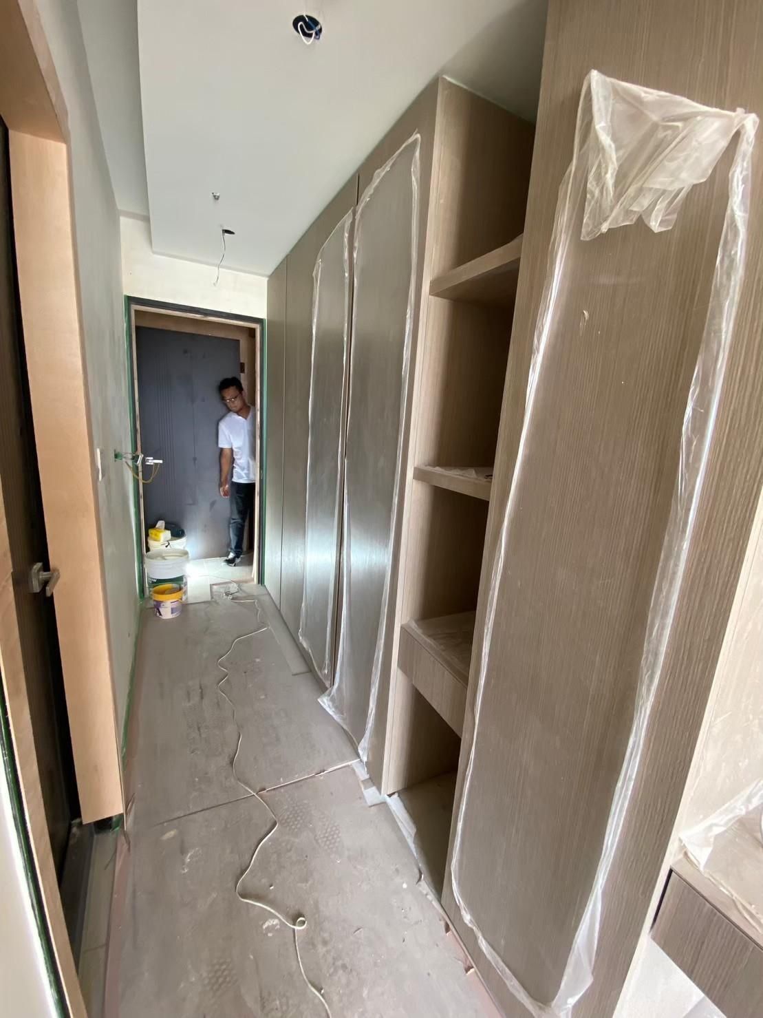 A man is standing in a hallway with a lot of shelves and cabinets.
