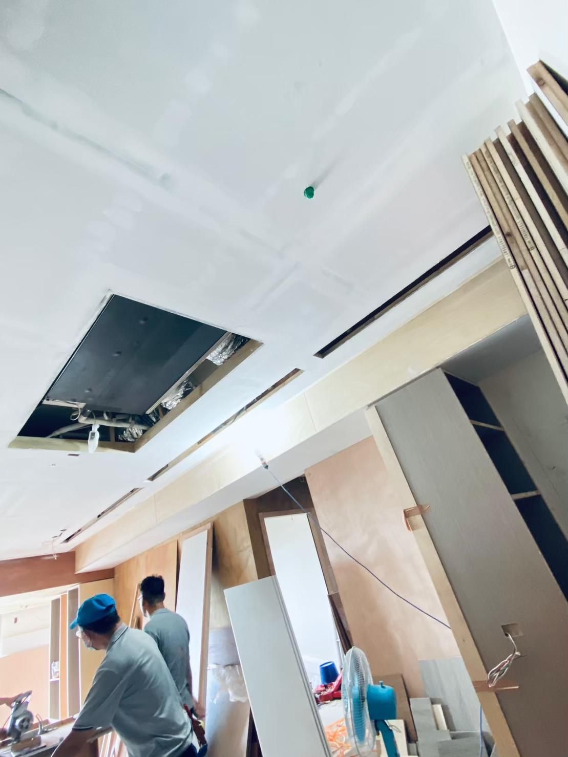 A group of people are working on a ceiling in a room.