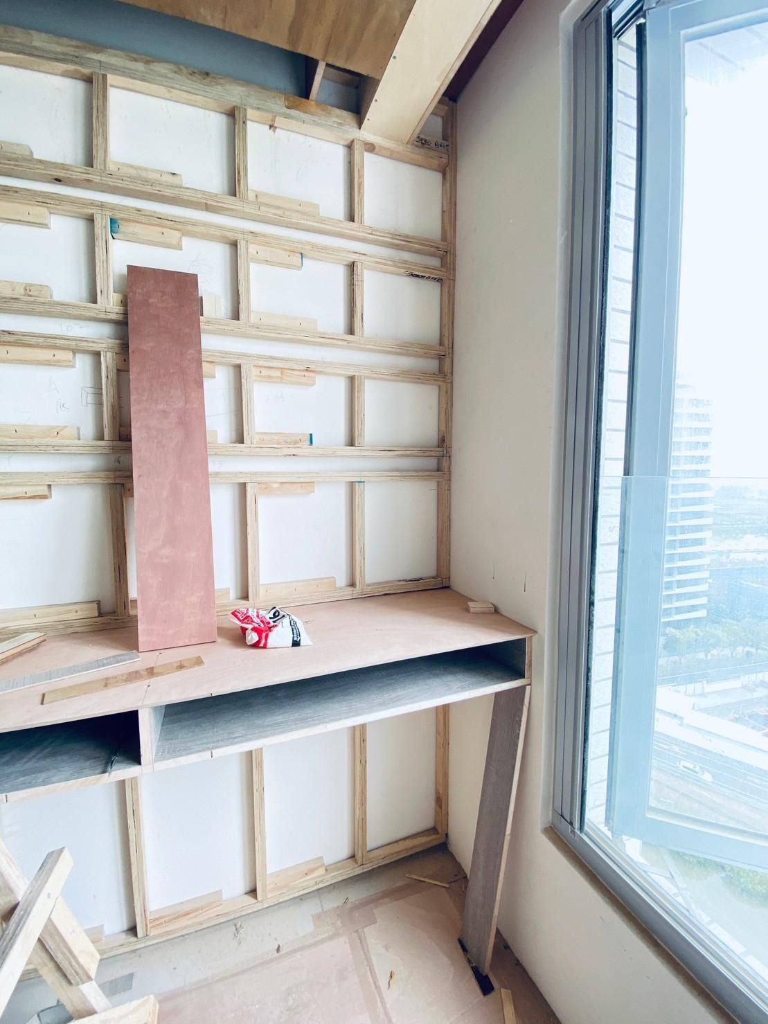 A room under construction with a desk and a window.