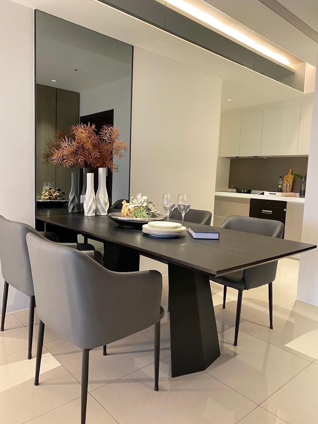 A dining room with a table and chairs and a large mirror on the wall.