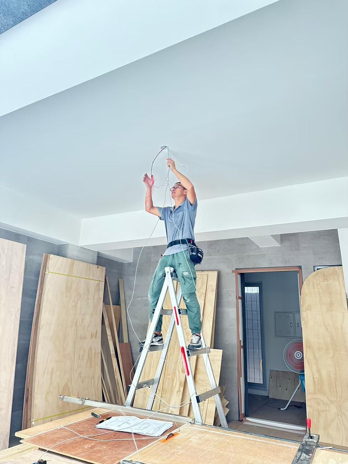 A man is standing on a ladder in a room.