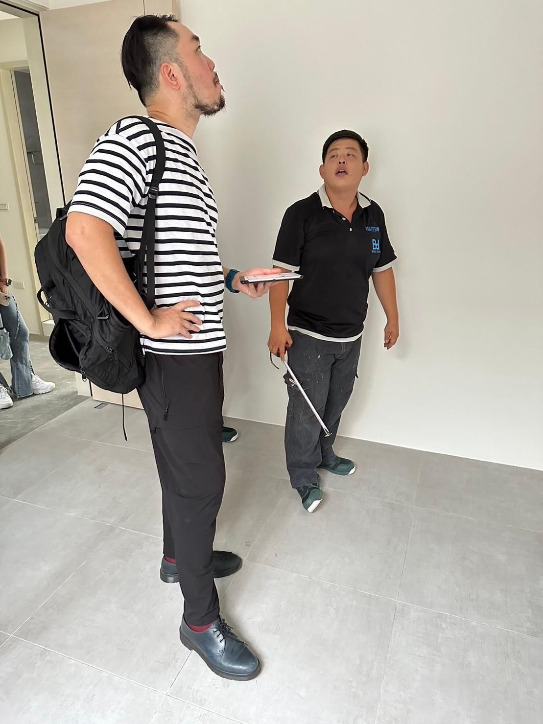 Two men are standing next to each other in an empty room.