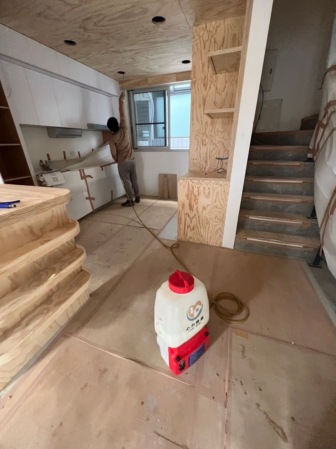 A bottle of milk is sitting on the floor in a kitchen.