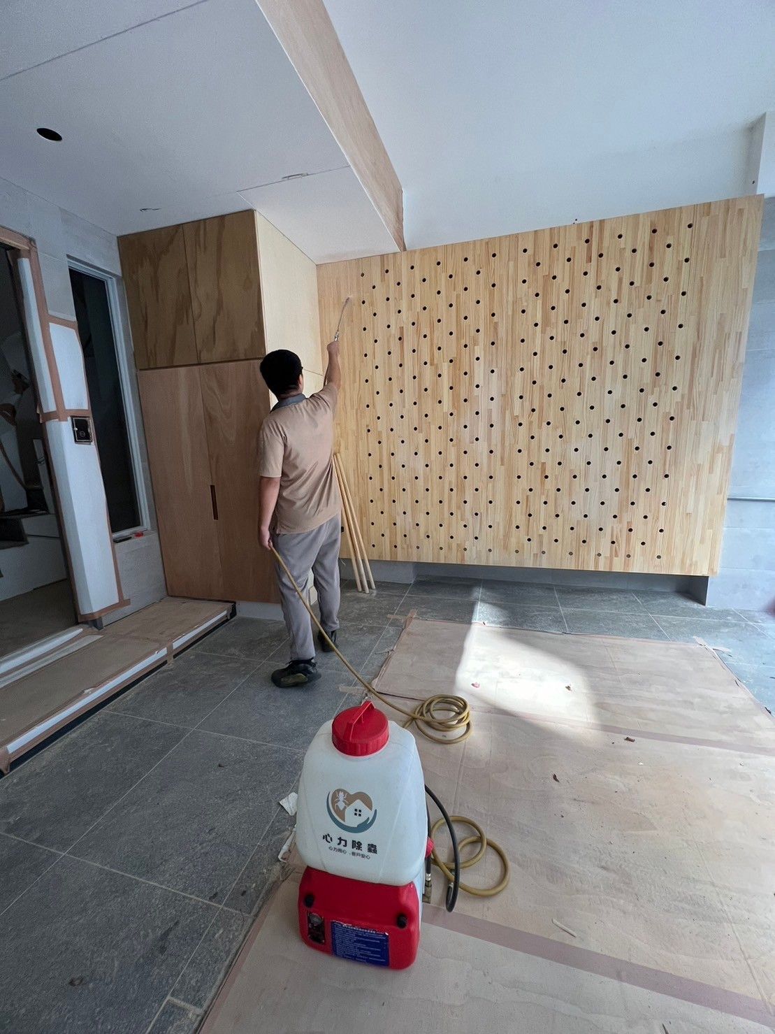 A man is standing next to a spray bottle in a room.
