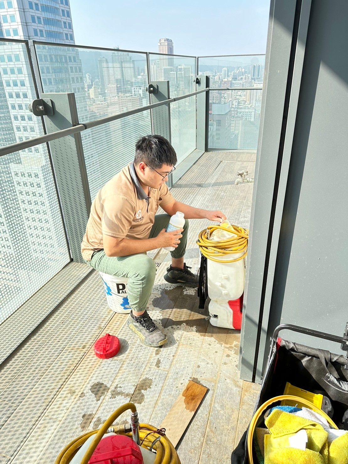 A man is sitting on a bucket on a balcony.