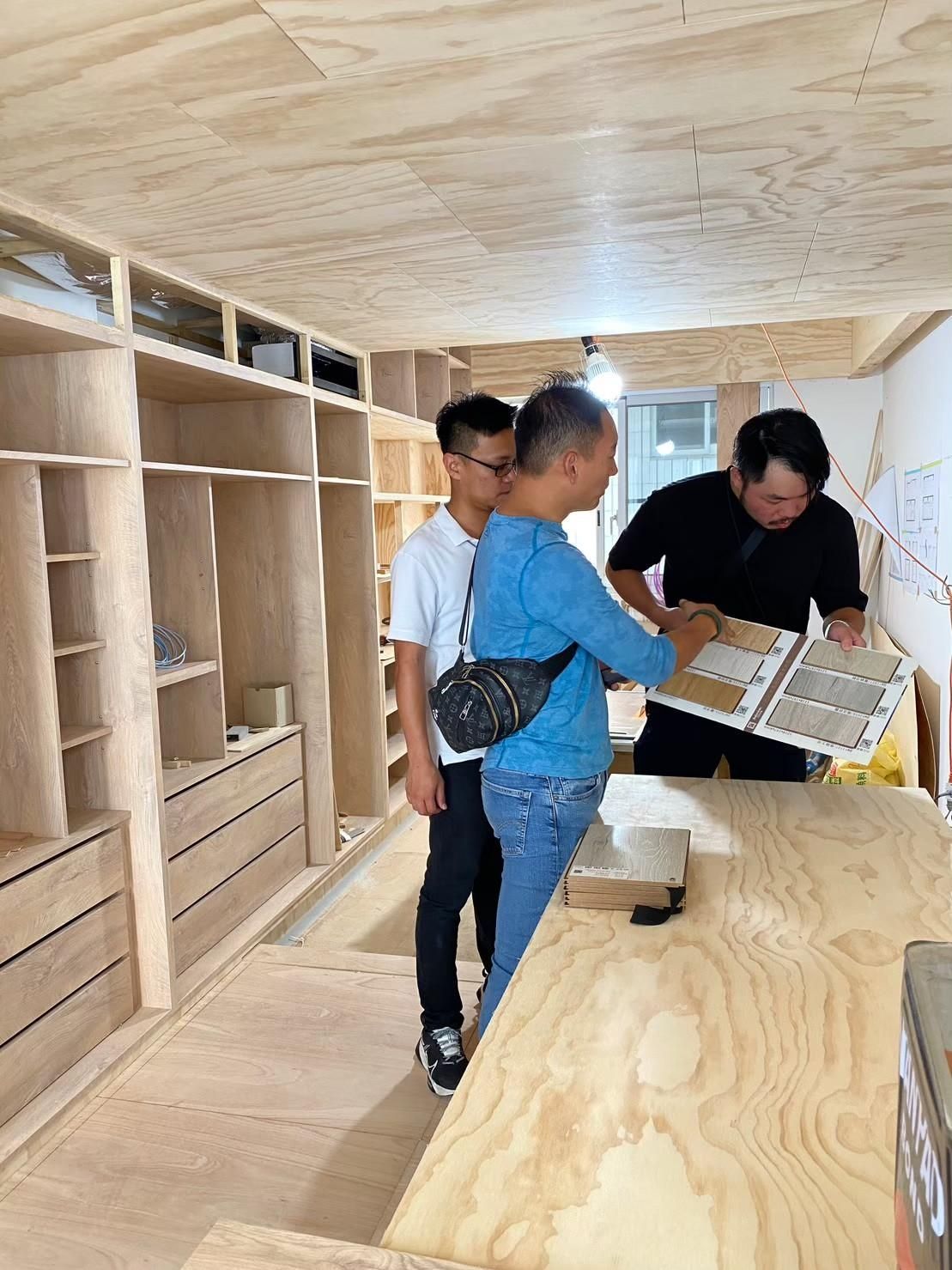 A group of men are standing in a room looking at a book.