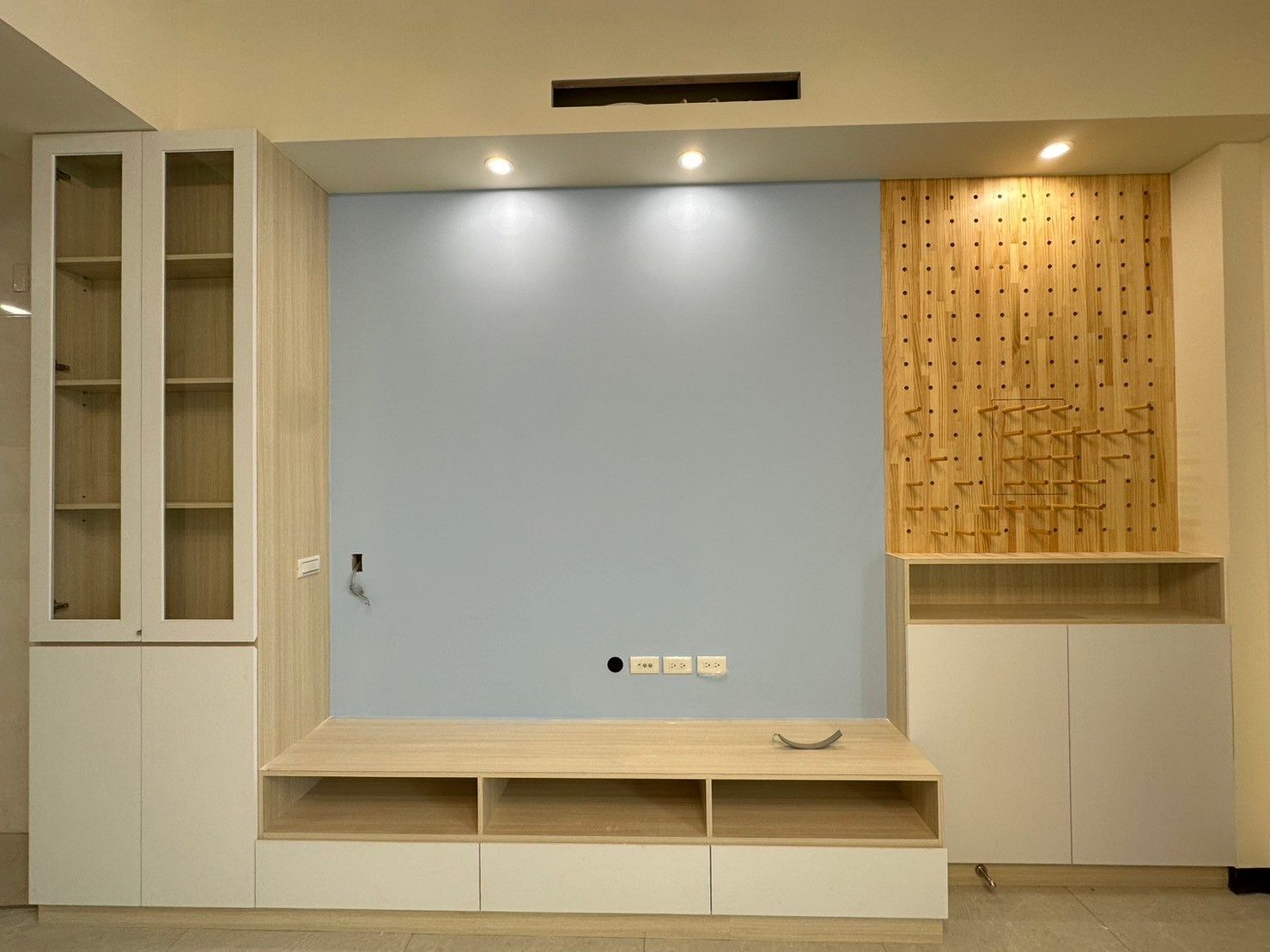 A living room with a blue wall and white cabinets