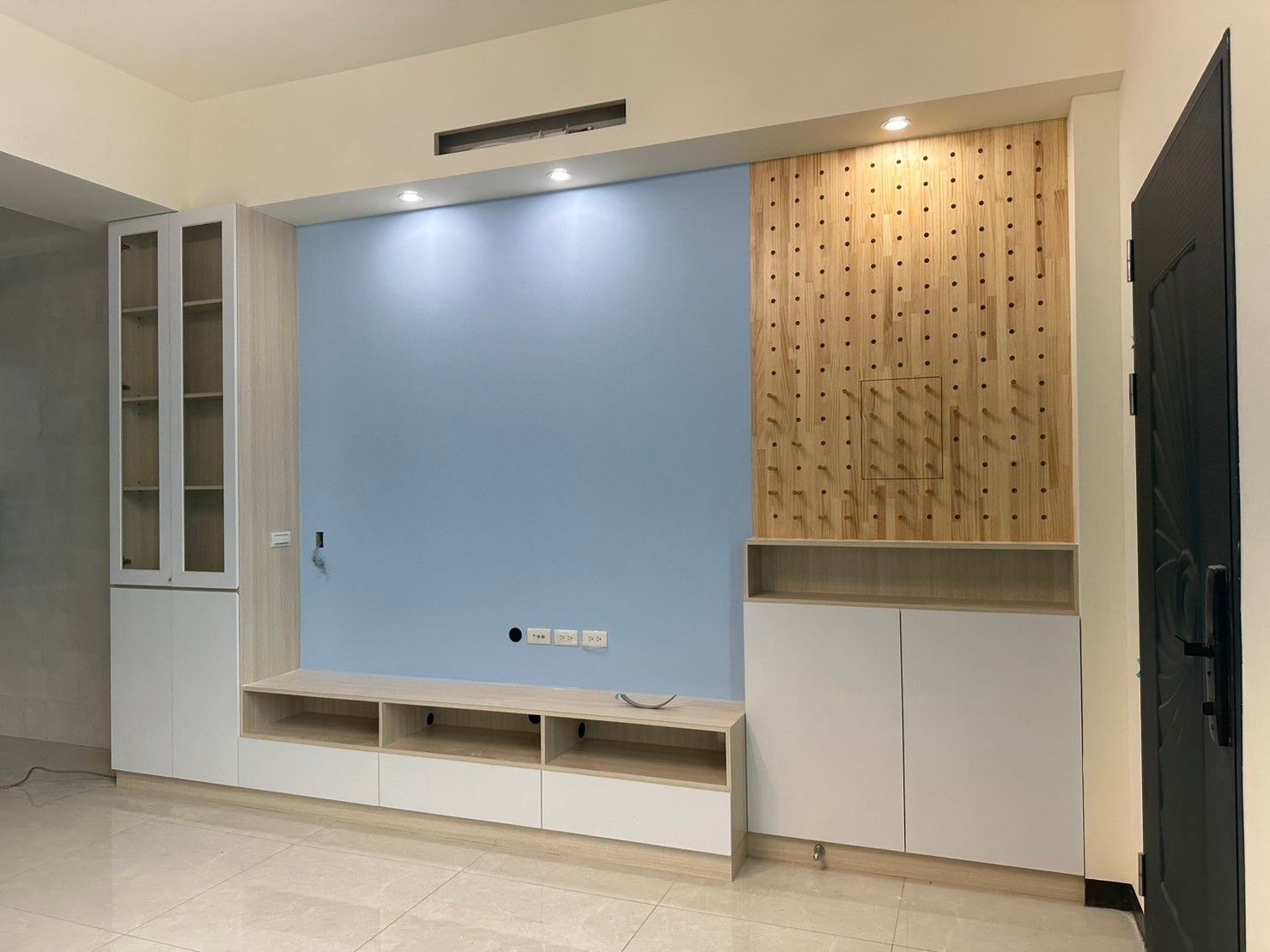 A living room with a blue wall and white cabinets.