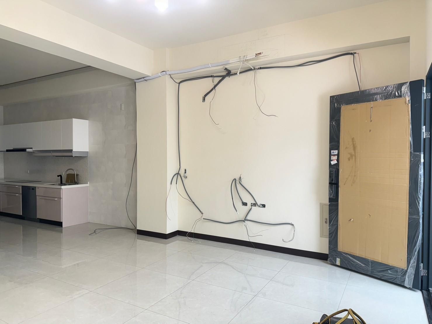 A living room with a door and a kitchen in the background.