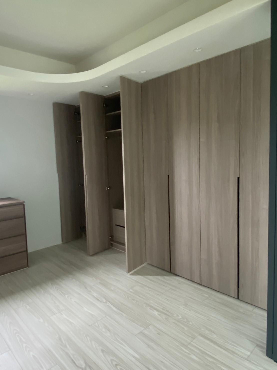 A bedroom with a lot of wooden cabinets and a dresser.