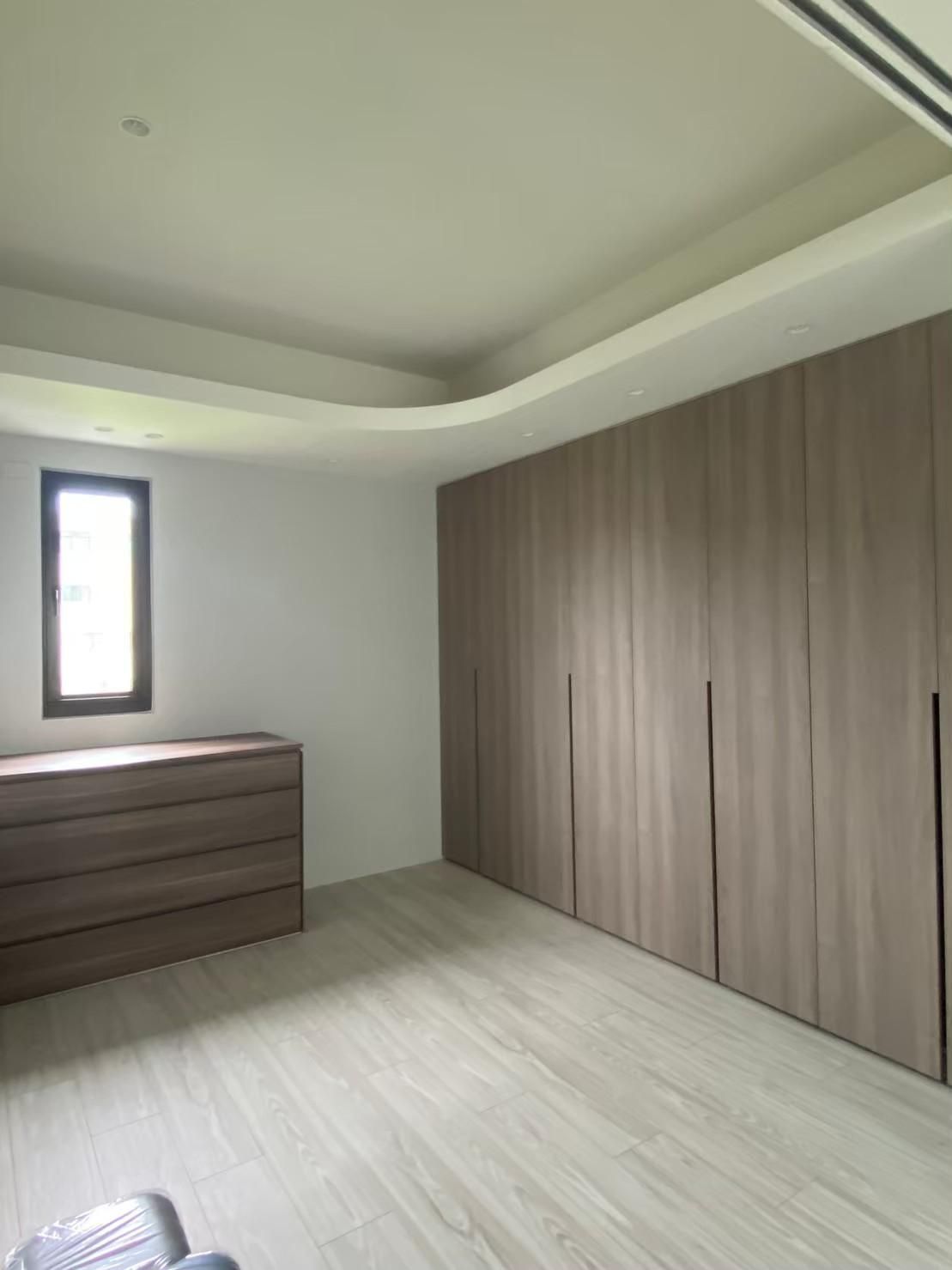 A room with a lot of wooden cabinets and a window.