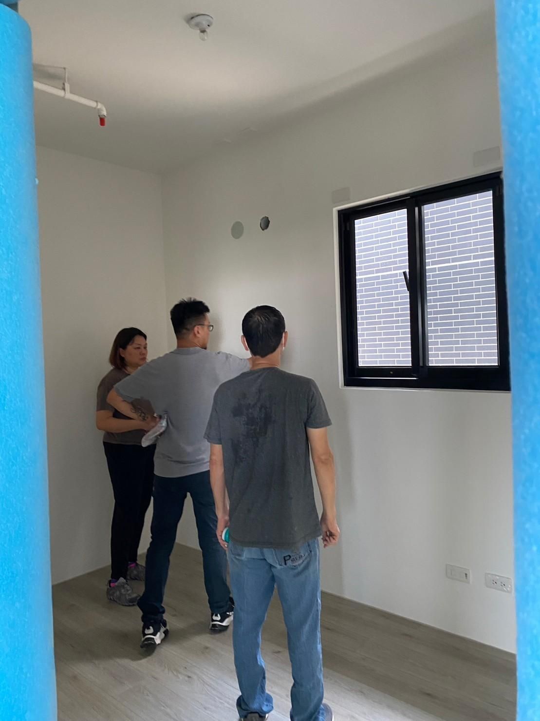 A group of people are standing in a room with a window.