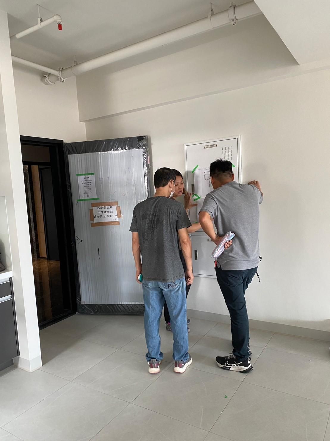 A group of men are standing in a room looking at a whiteboard.