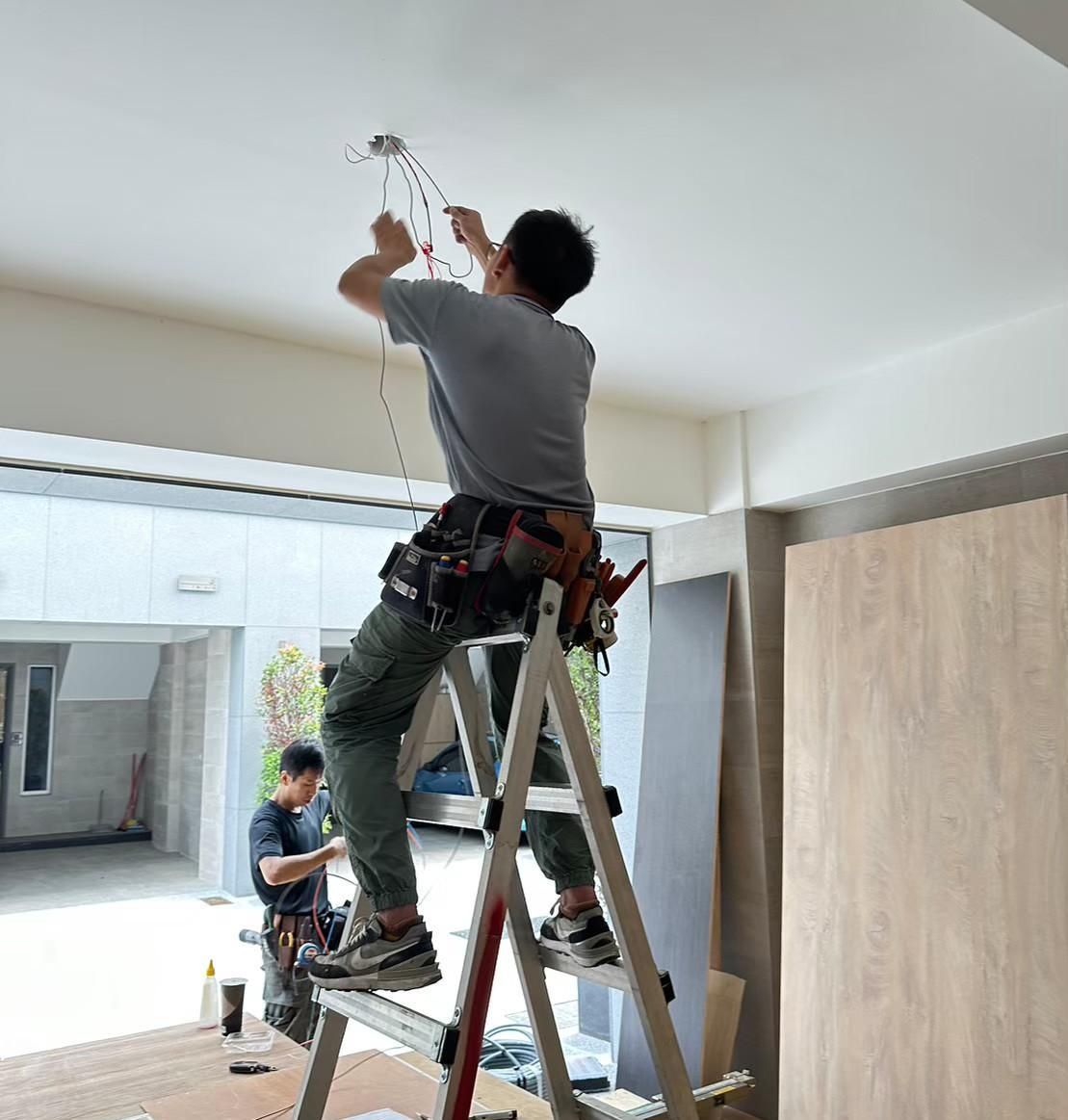 A man is standing on a ladder working on a ceiling.