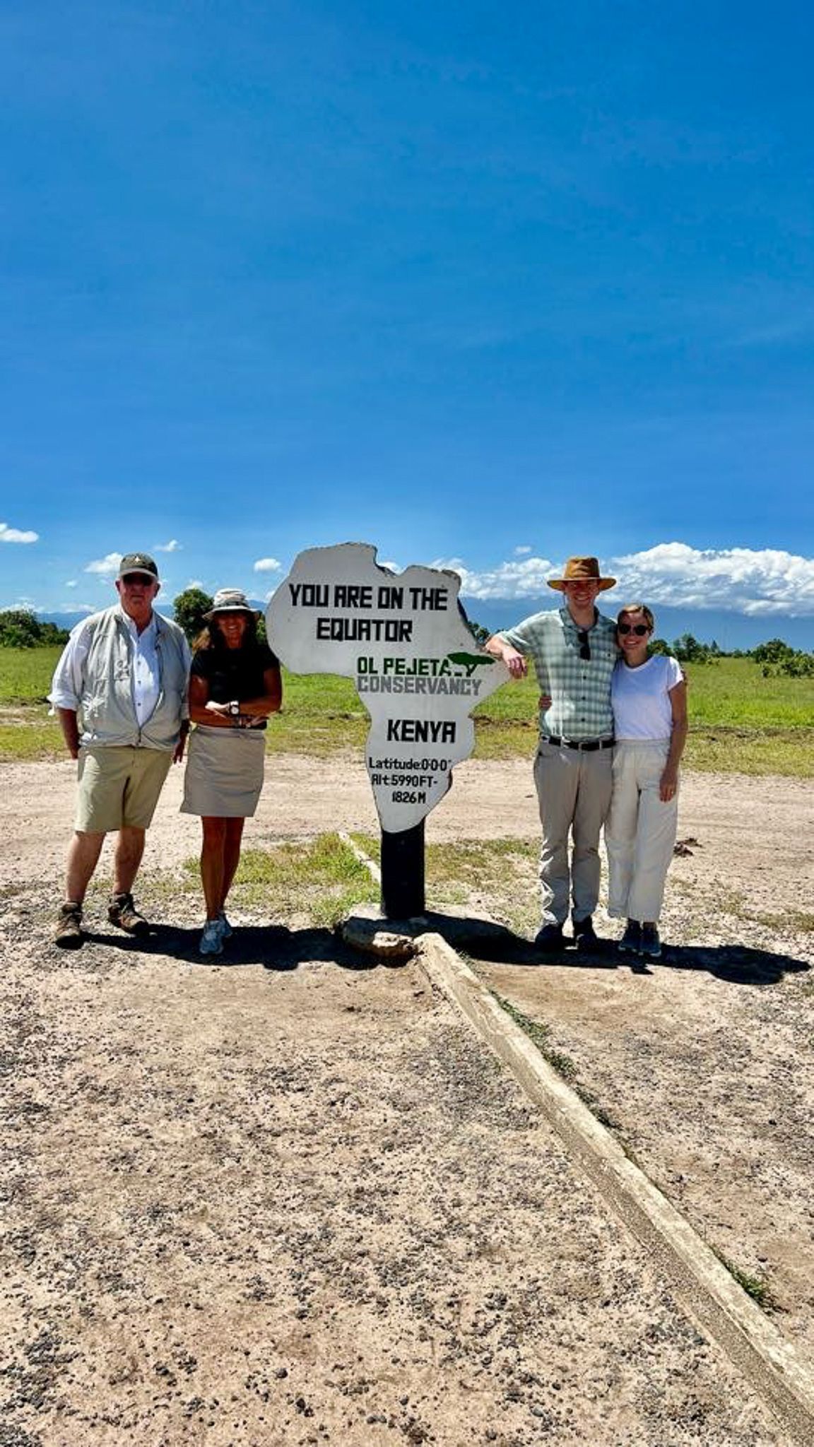 A group of people standing next to a sign in a field.