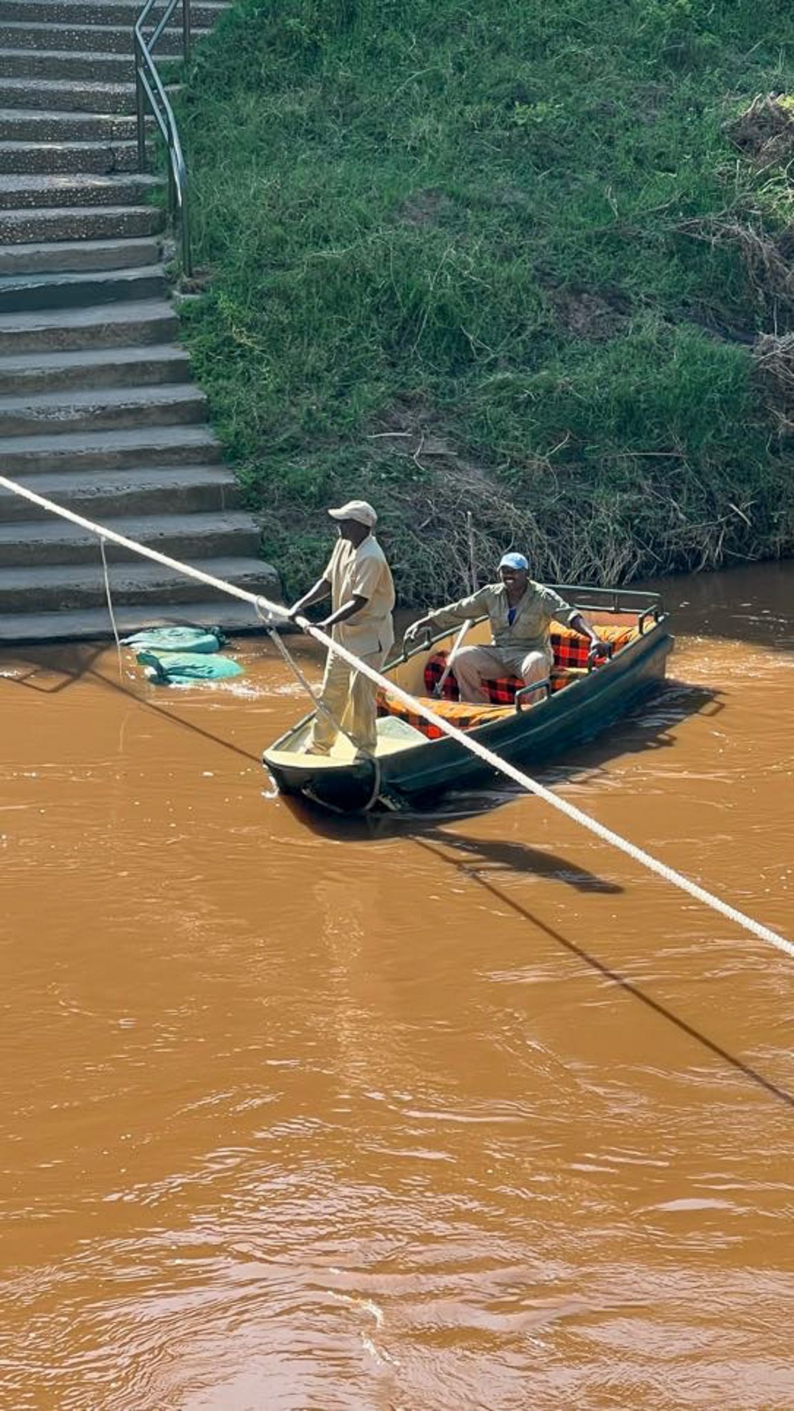 A man is standing in a boat in the middle of a river.