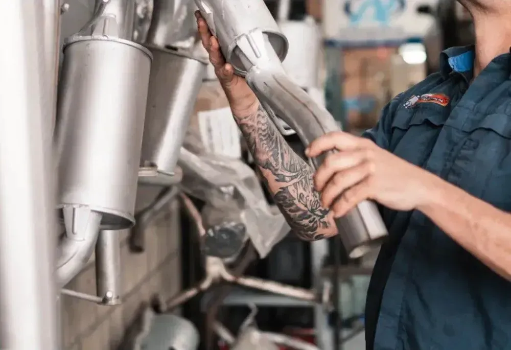 Man Holding Car Exhaust — Exhaust & Muffler Repairs in Port Macquarie, NSW