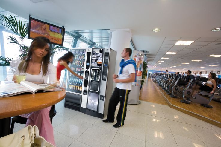 a man standing next to a vending machine in a gym