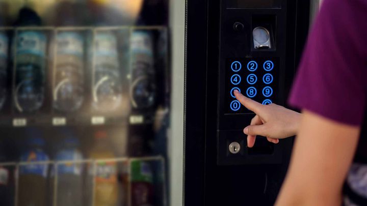 a person is pressing a button on a vending machine .