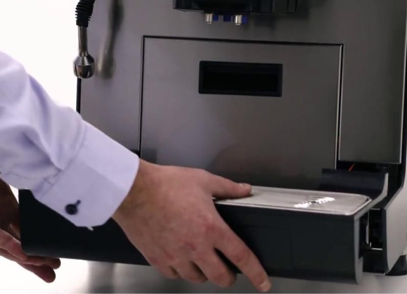 a man in a white shirt is opening a coffee machine