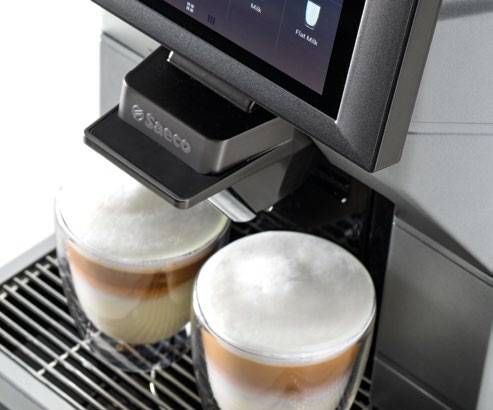 two cups of cappuccino are being made in a saeco coffee machine