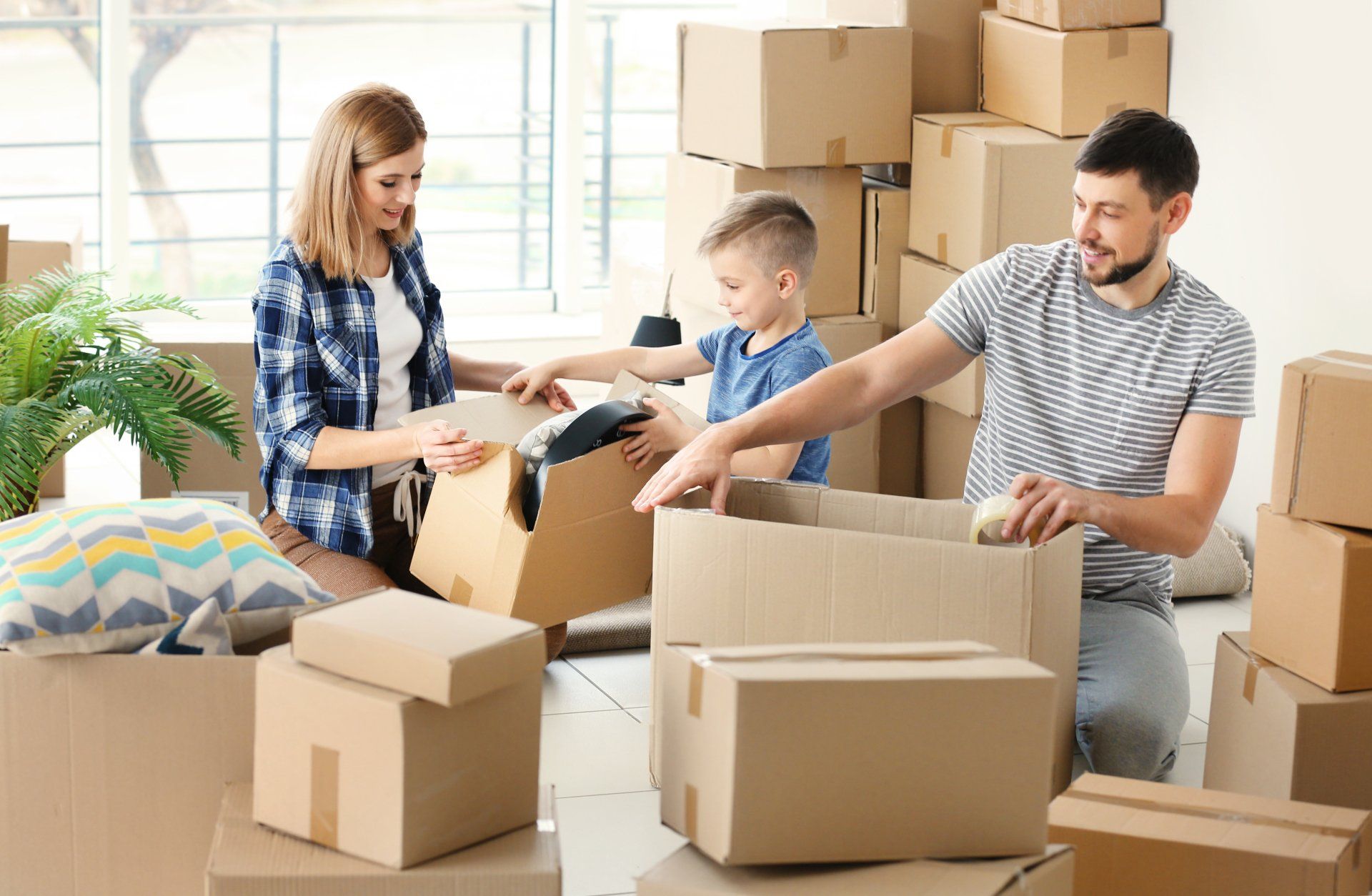 A family is packing boxes in a living room.