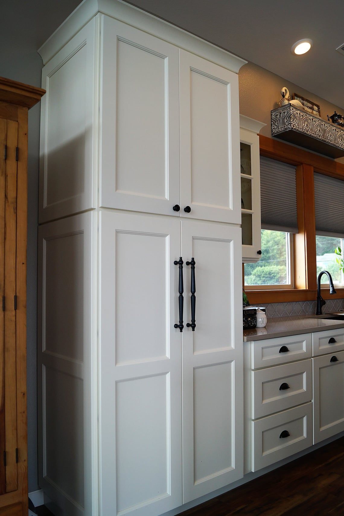 Kitchen with black microwave, wood cabinets, brick backsplash, and red kettle on a wooden counter.