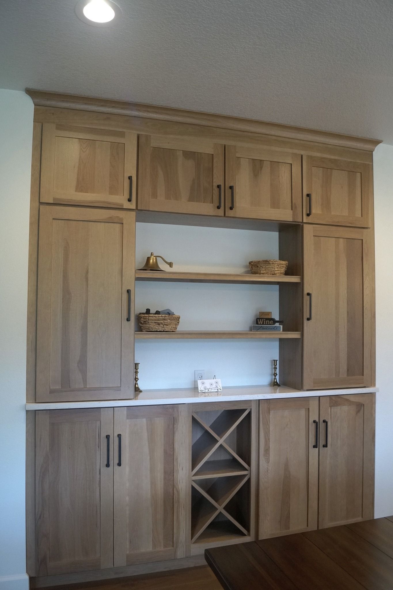 Built-in wooden wall unit with cabinets, shelves, and a wine rack in a room