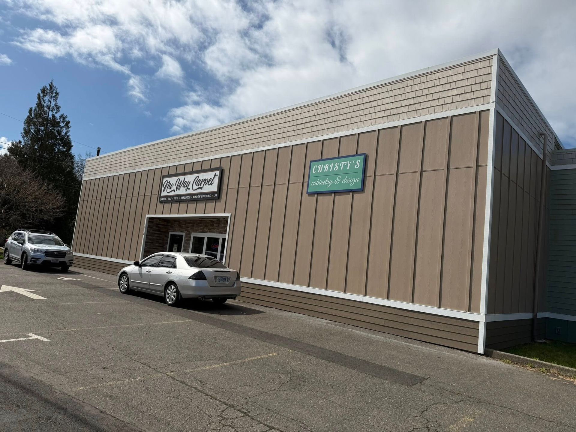 Commercial storefront with two parked cars under a bright blue sky