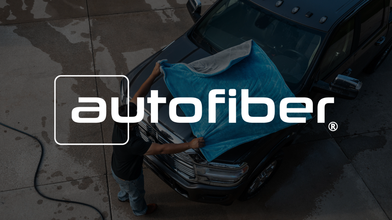 A person is washing a car with a towel and the logo for autofiber