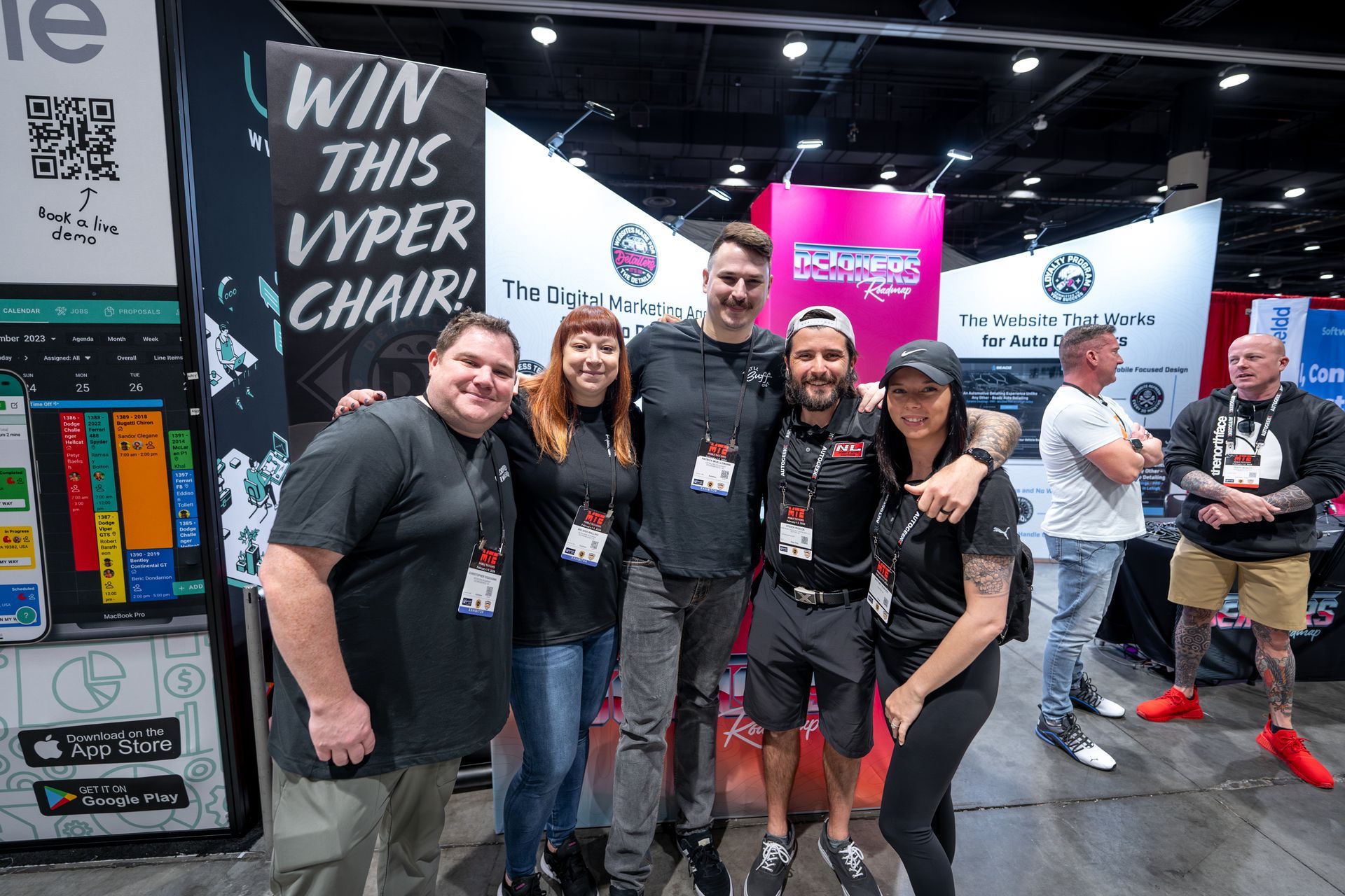 Group of people at a trade show booth. They are smiling and posing for the camera.