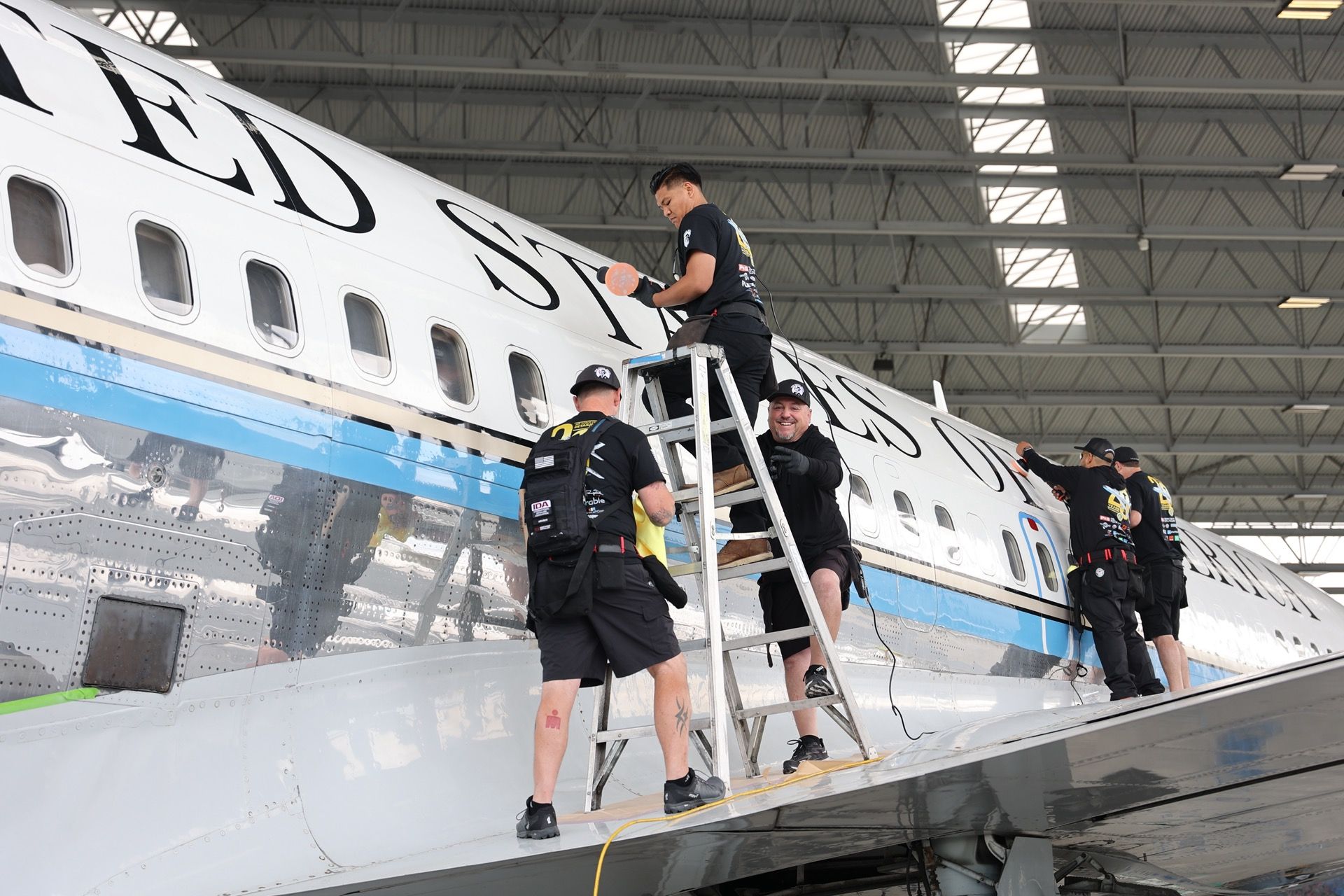 A group of men are working on an airplane in a hangar.