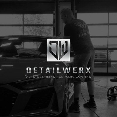 A man is standing next to a car in a garage.