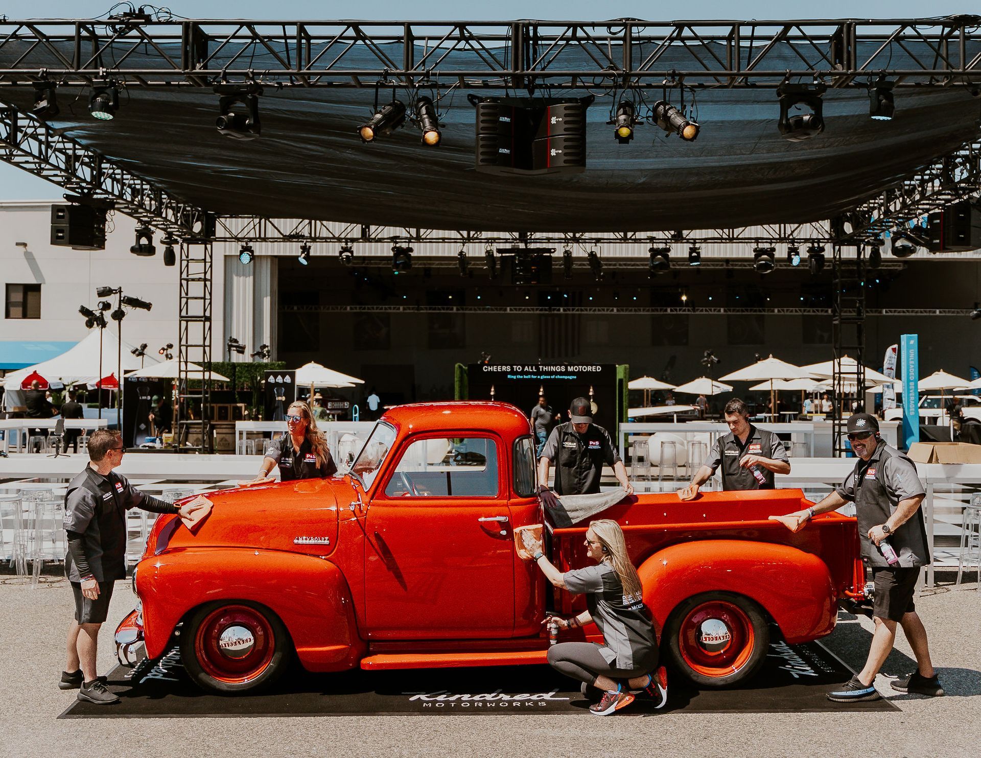a group of people are working on an old red truck .