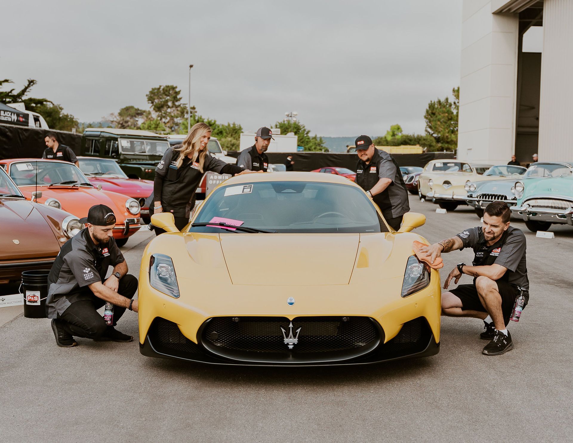 a group of people are working on a yellow sports car .