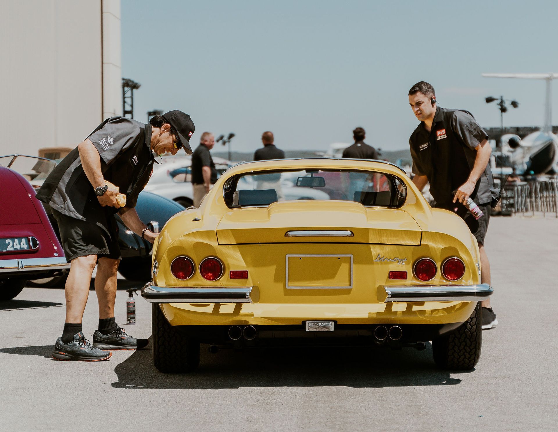two men are working on a yellow sports car in a parking lot .