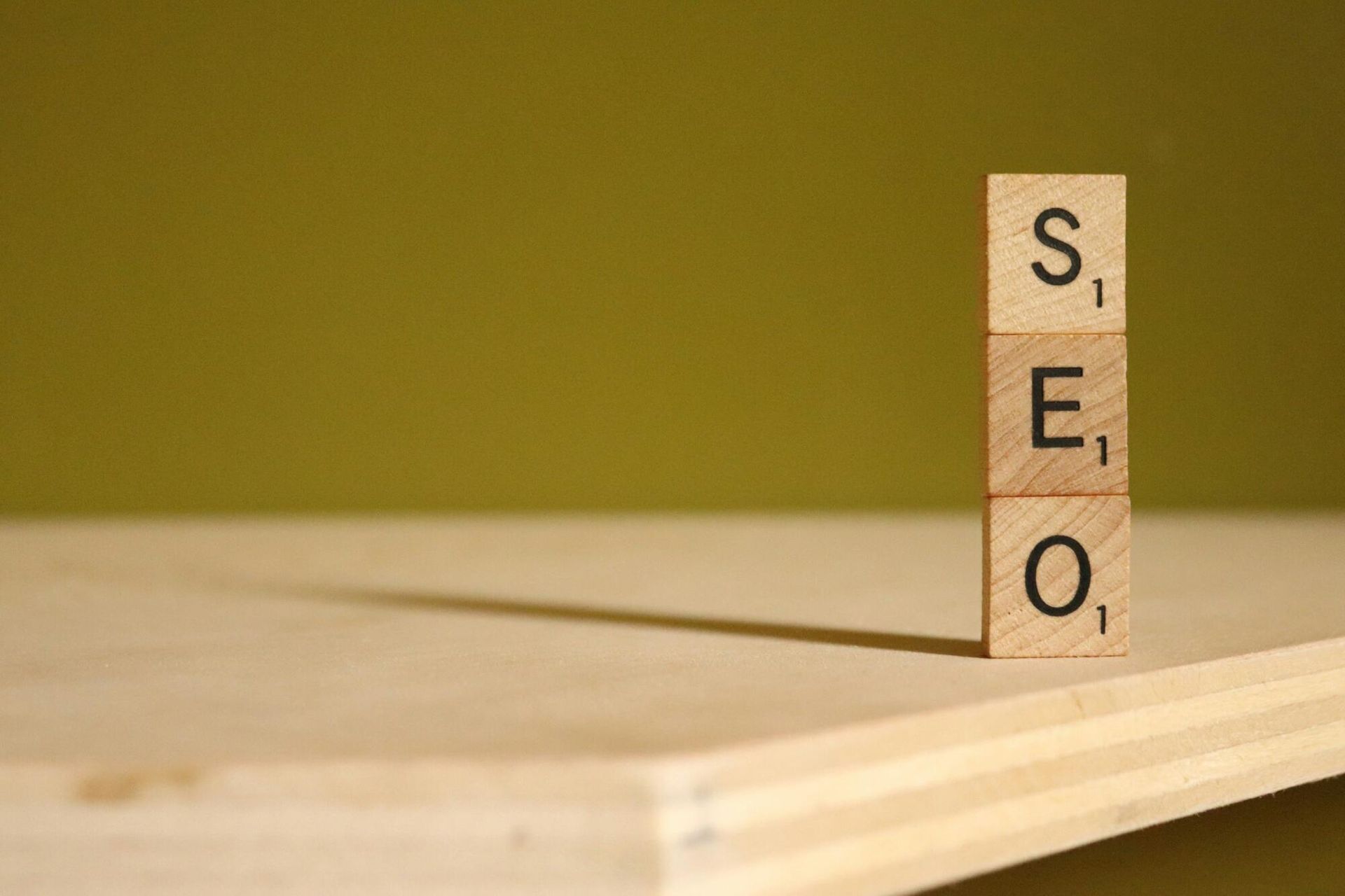 A wooden block with the letters seo stacked on top of each other on a wooden table.