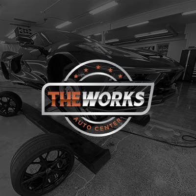 A black and white photo of a car being worked on by the works auto center