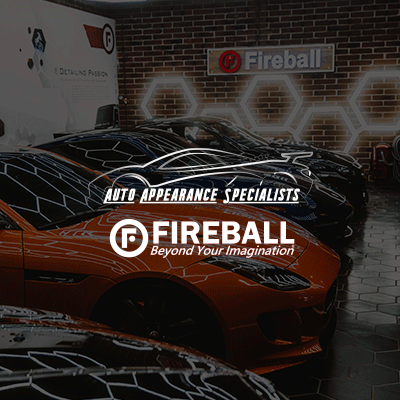 A row of cars are parked in front of a brick wall.