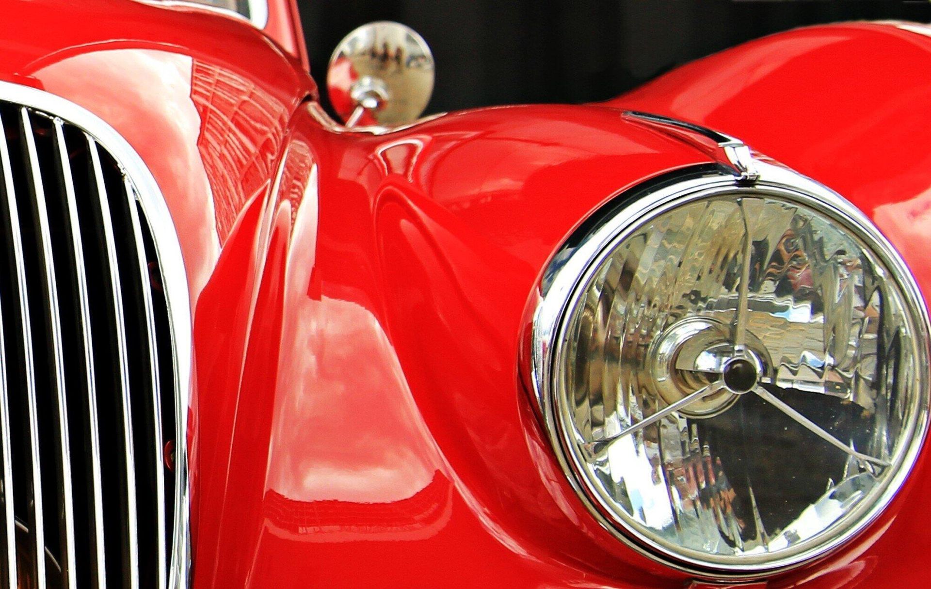 A close up of a red car 's headlight and grille