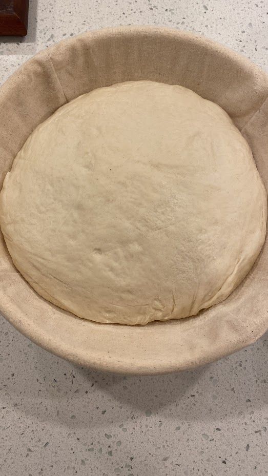 A bowl of dough is sitting on a counter.