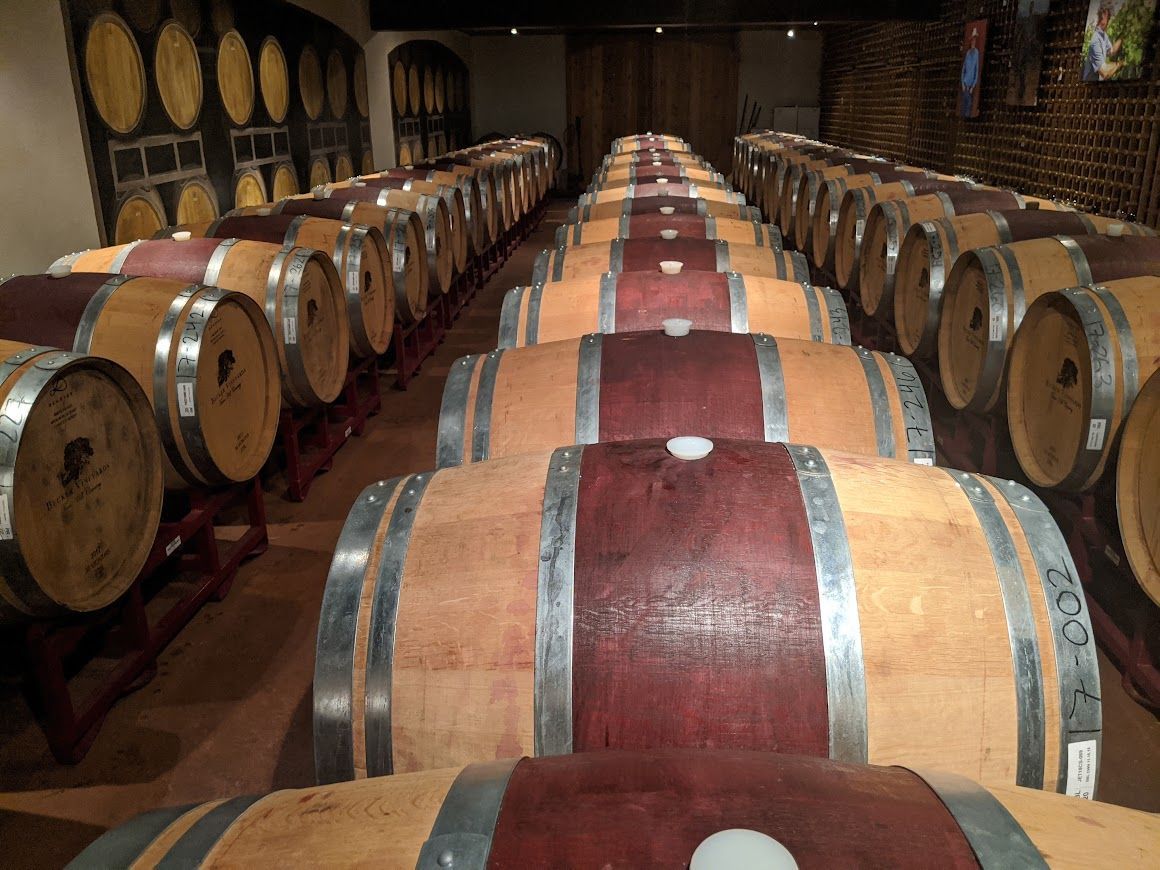 A row of wine barrels are lined up in a wine cellar.